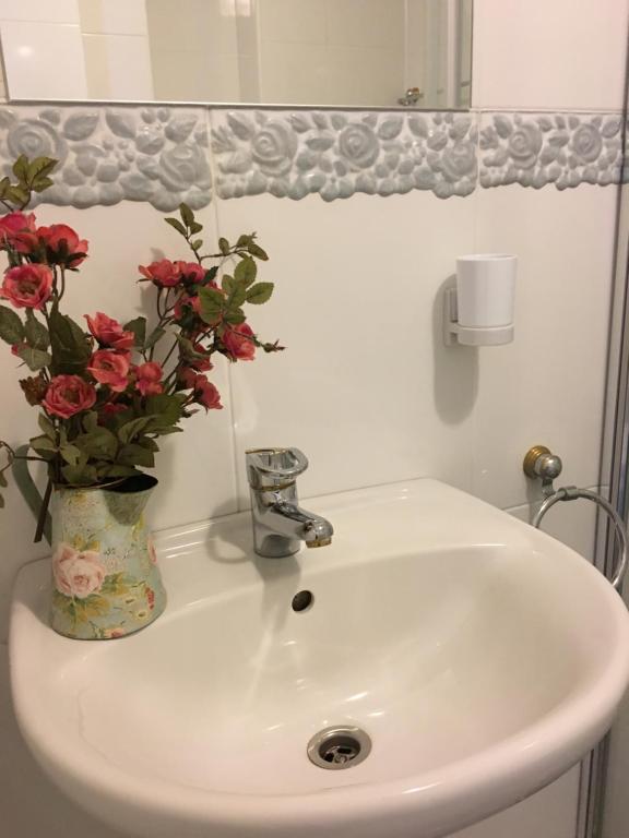 a bathroom sink with a vase of flowers on it at Kurenas in Juodkrantė