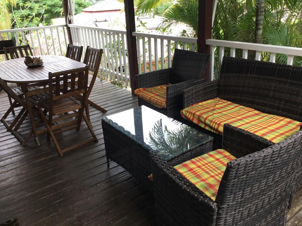 een veranda met 2 stoelen en een tafel en stoelen bij Gite Palmier in Bouillante