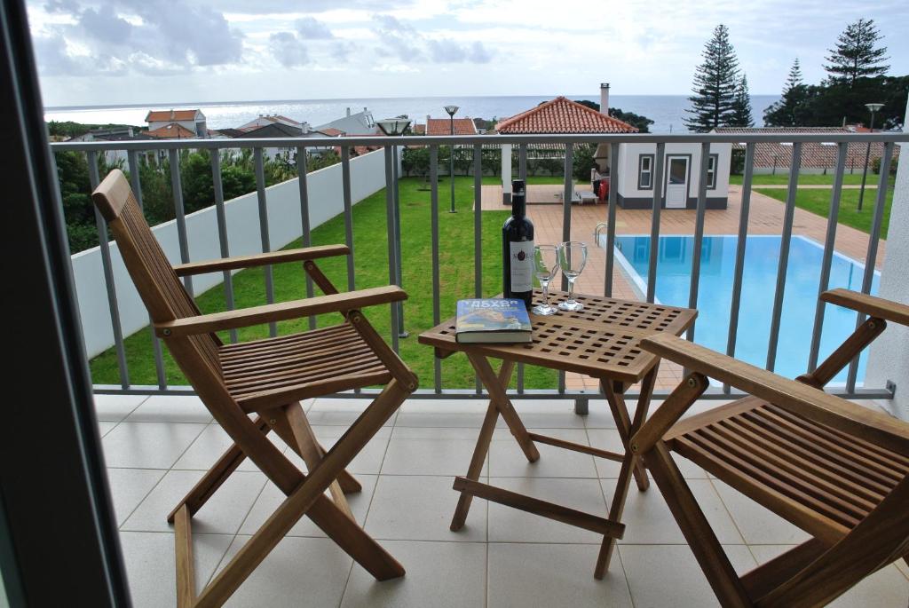 a table with a bottle of wine and two chairs on a balcony at CASA SIMBA , where the fun begins in Ponta Delgada