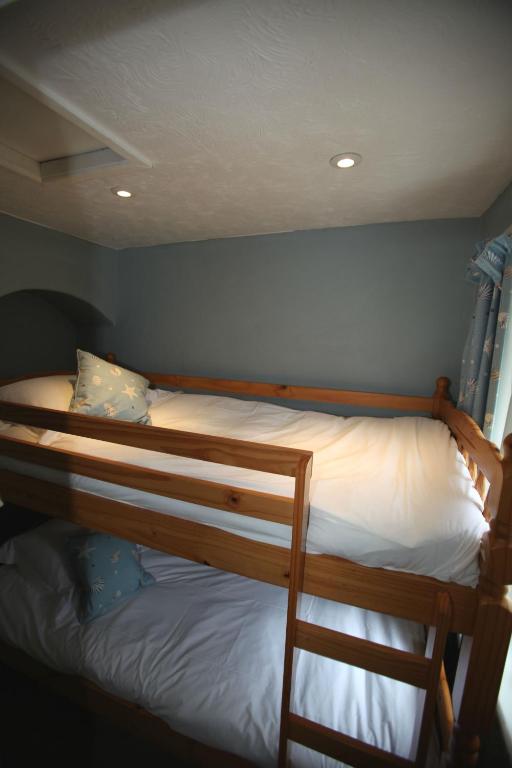 a bedroom with two bunk beds with white sheets at Fernhill Hotel in Lyme Regis
