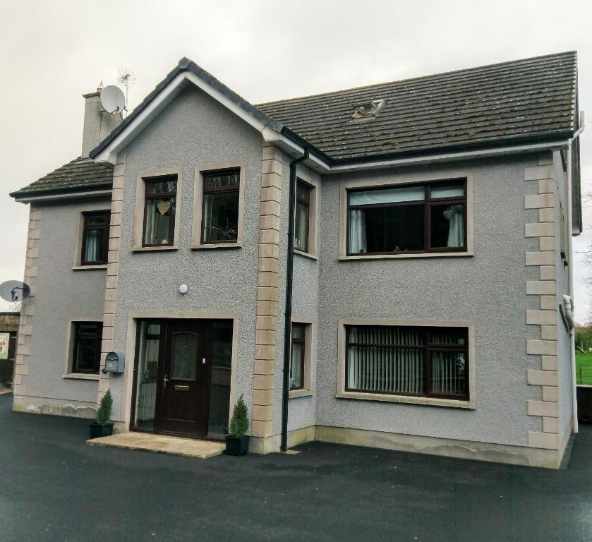 uma casa cinzenta com uma porta e janelas em The Tree-house B&B em Ballymena