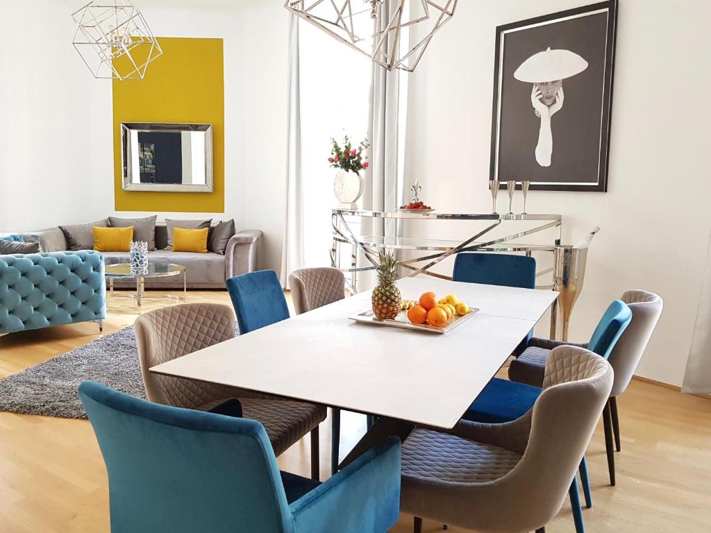 ein Esszimmer mit einem weißen Tisch und blauen Stühlen in der Unterkunft Belle Epoque in Wien