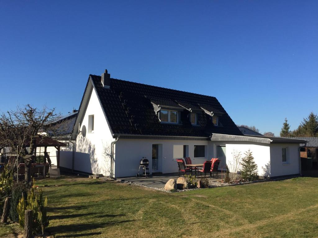 a white house with a black roof and a yard at Ferienhaus BAUMBLÜTE in Werder