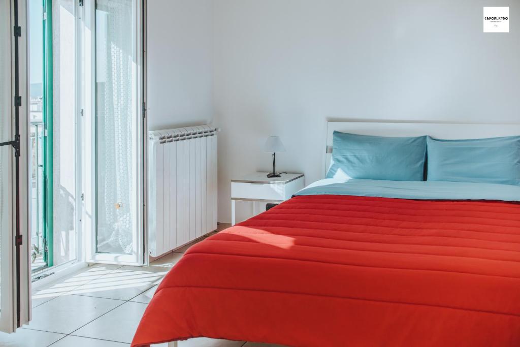 un letto rosso in una stanza con finestra di Caporlando B&B a Castellaneta