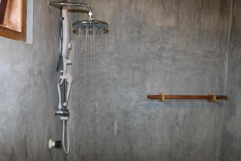 La salle de bains est pourvue d'une douche avec un pommeau de douche. dans l'établissement Cili Hotel, à Baie d'Arugam
