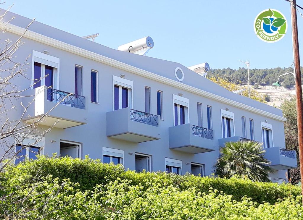 a white building with blue windows and bushes at Point Twins Apartments in Vrontádos