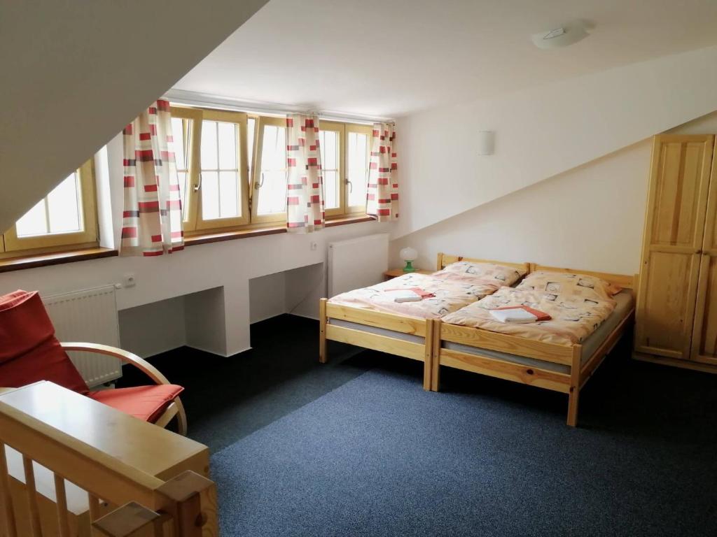 1 dormitorio con 1 cama, 1 silla y ventanas en Apartman U Hippolyta en Jindrichuv Hradec