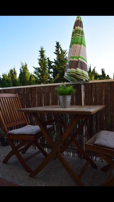 - une table de pique-nique avec 2 chaises et un parasol sur une clôture dans l'établissement Les Lilas, à Hyères