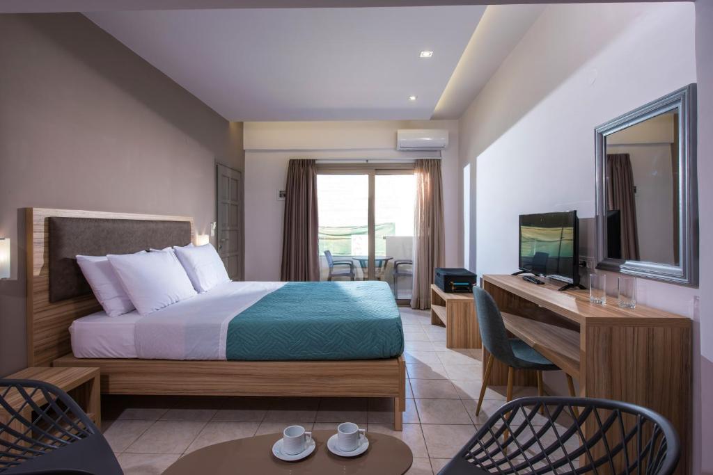 a hotel room with a bed and a desk and a television at Thania Seaside Smotel - Adults Only in Agia Pelagia