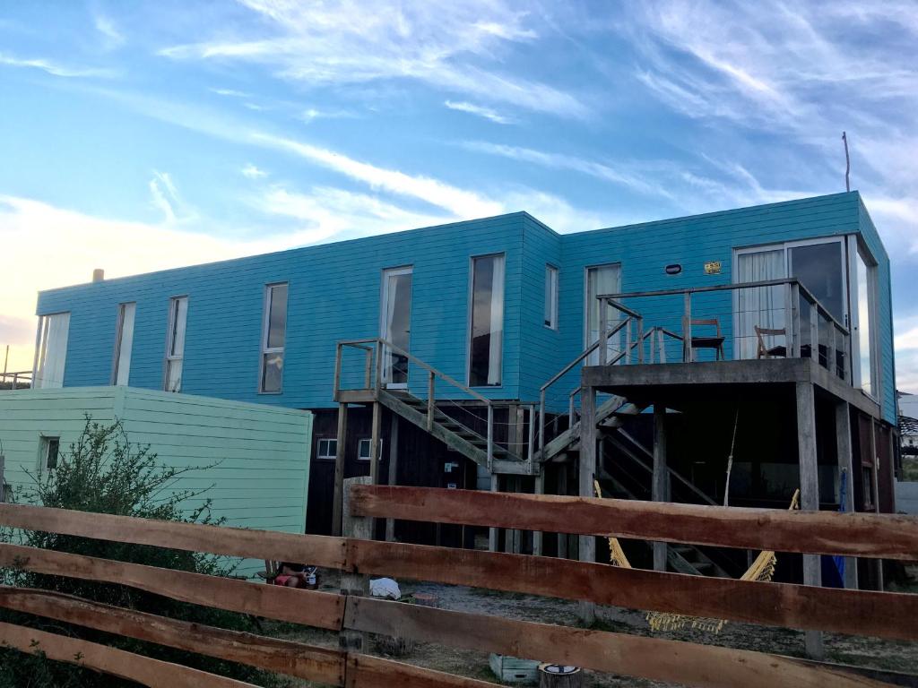 una casa azul con una valla delante de ella en Hostel Vente al Diablo, en Punta del Diablo