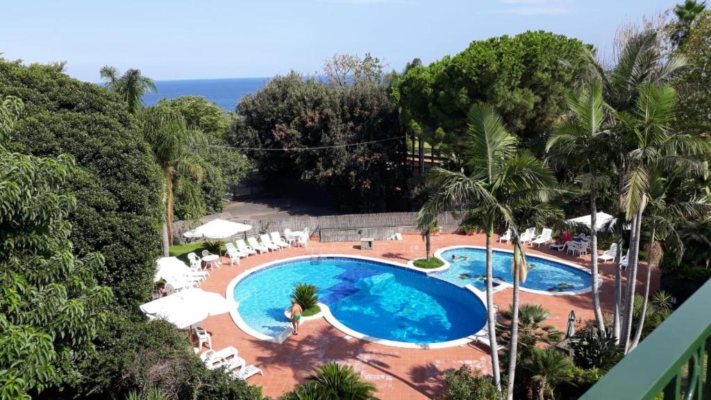Una vista aérea de una piscina con sillas y el océano. en andrew's apartment - mulinia residence, en Acireale