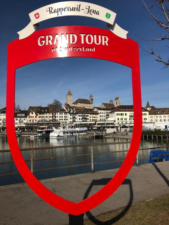 a red sign in front of a river with buildings at Ferienwohnung Rapperswil in Rapperswil-Jona