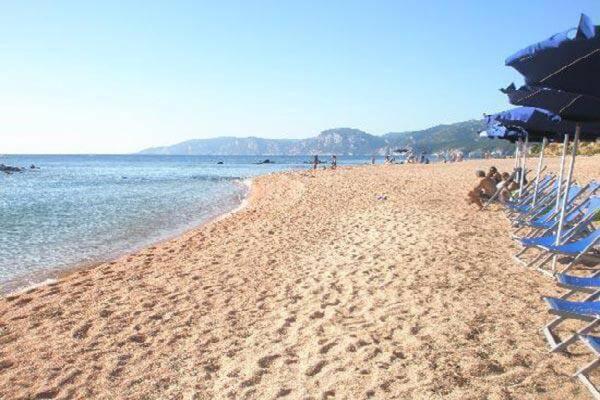 a sandy beach with chairs and umbrellas on it at casa mariolu 2 in Cala Gonone
