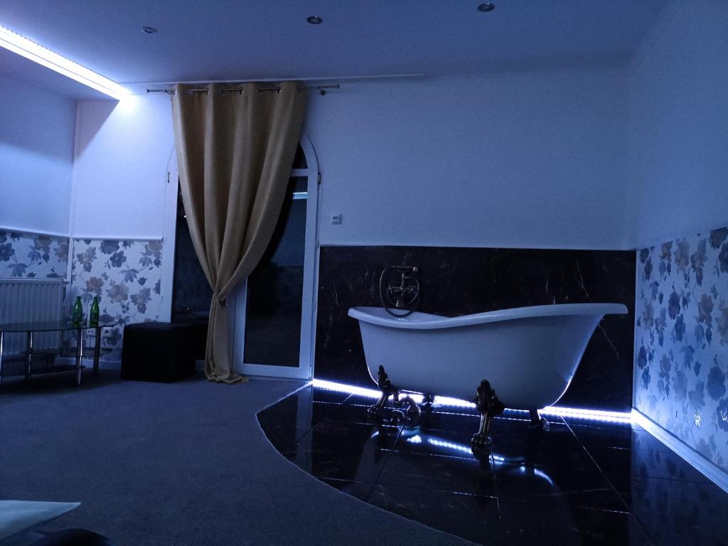 W niebieskim pokoju znajduje się łazienka z białą wanną. w obiekcie Hotel Tara w Kielcach