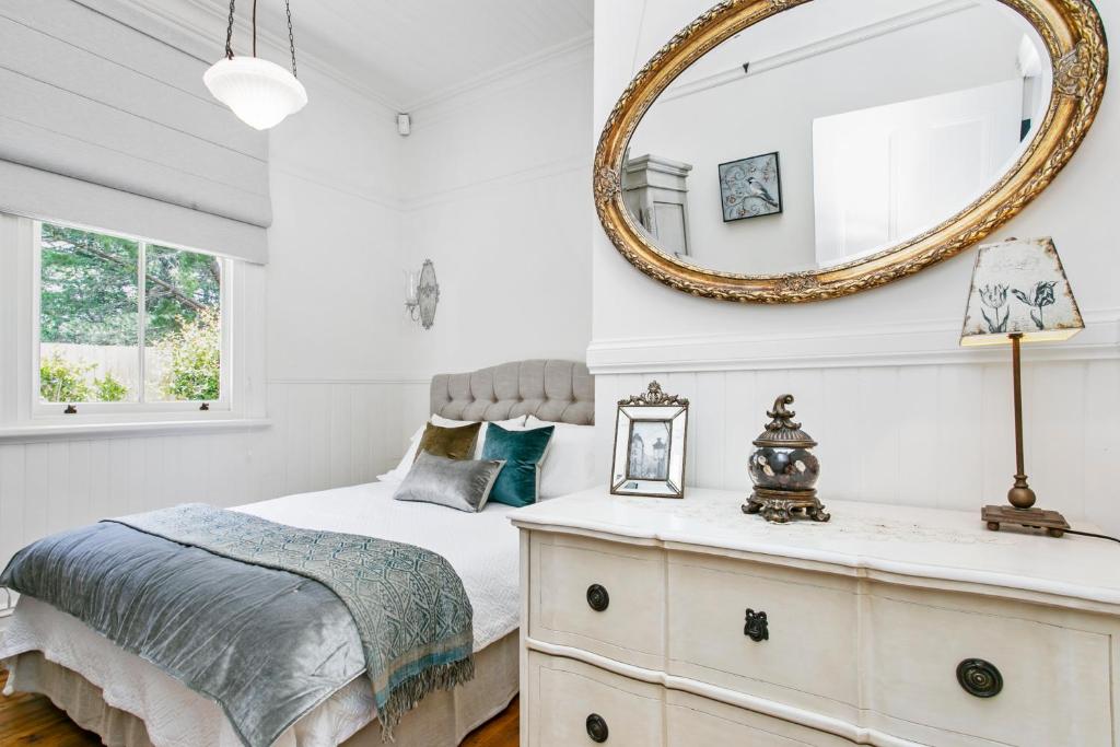 ein Schlafzimmer mit einem Bett und einem Spiegel in der Unterkunft Gowan Brae Cottage in Katoomba