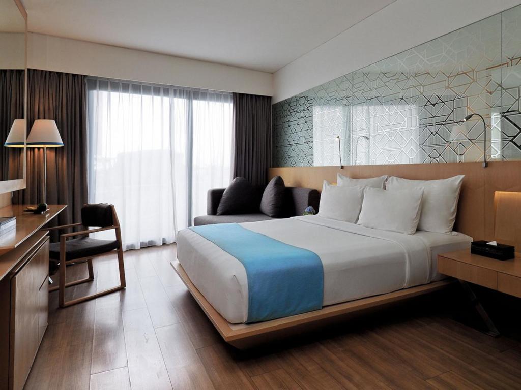 ein Hotelzimmer mit einem großen Bett und einem Schreibtisch in der Unterkunft IZE Seminyak by LifestyleRetreats in Seminyak