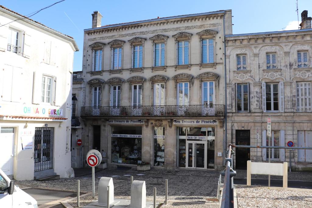 un gran edificio de piedra con balcón en una calle en Residence du marche, en Jonzac