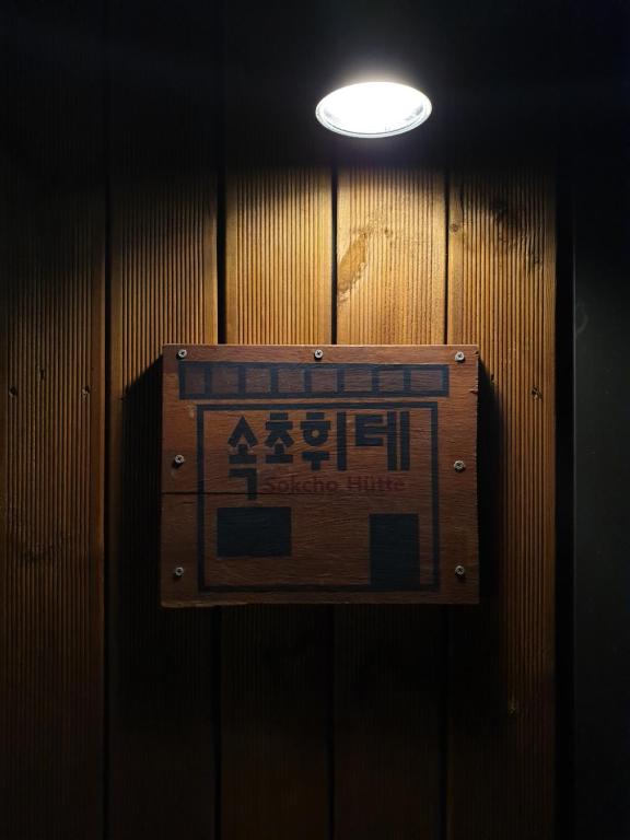 a sign on a wooden wall with a light at Sokcho Hutte in Sokcho
