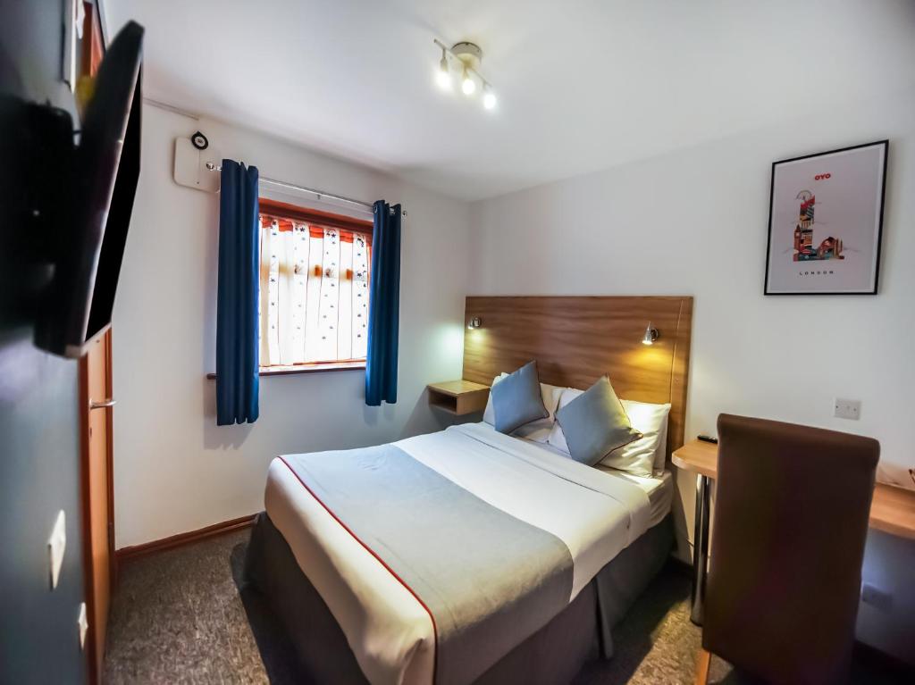 a hotel room with a bed and a desk at OYO Arinza Hotel, London Ilford in Ilford