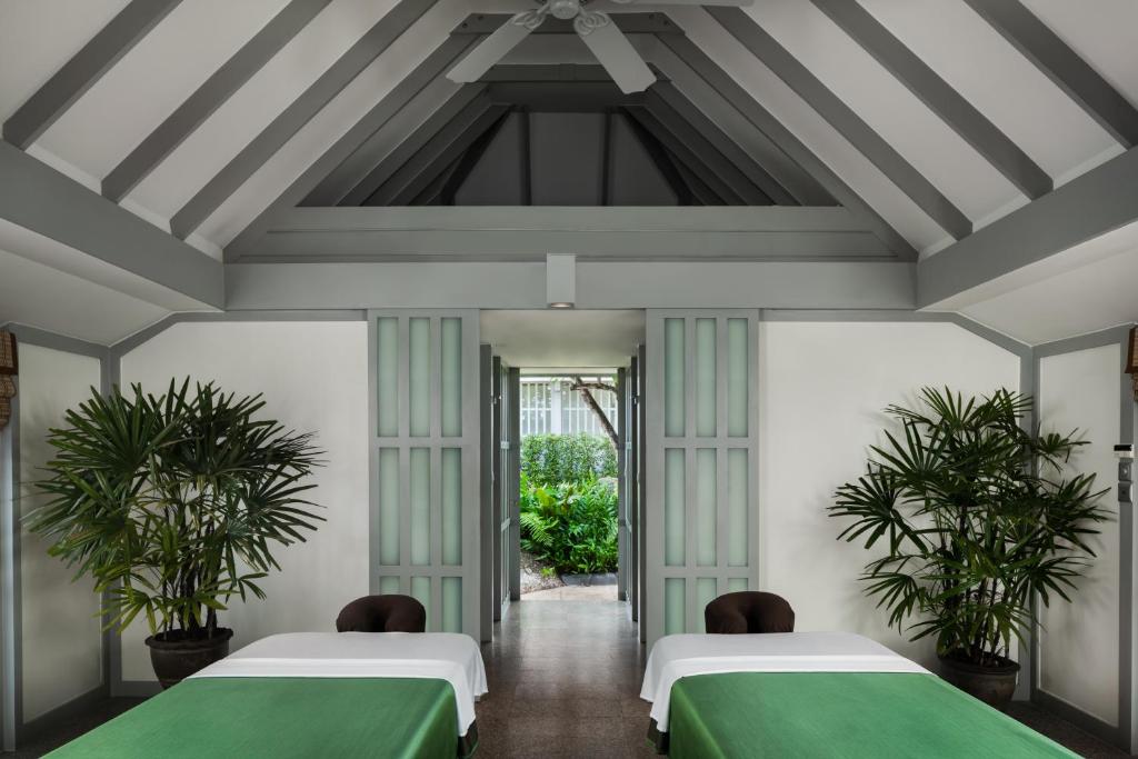 two beds in a room with two plants at The Surin Phuket in Surin Beach