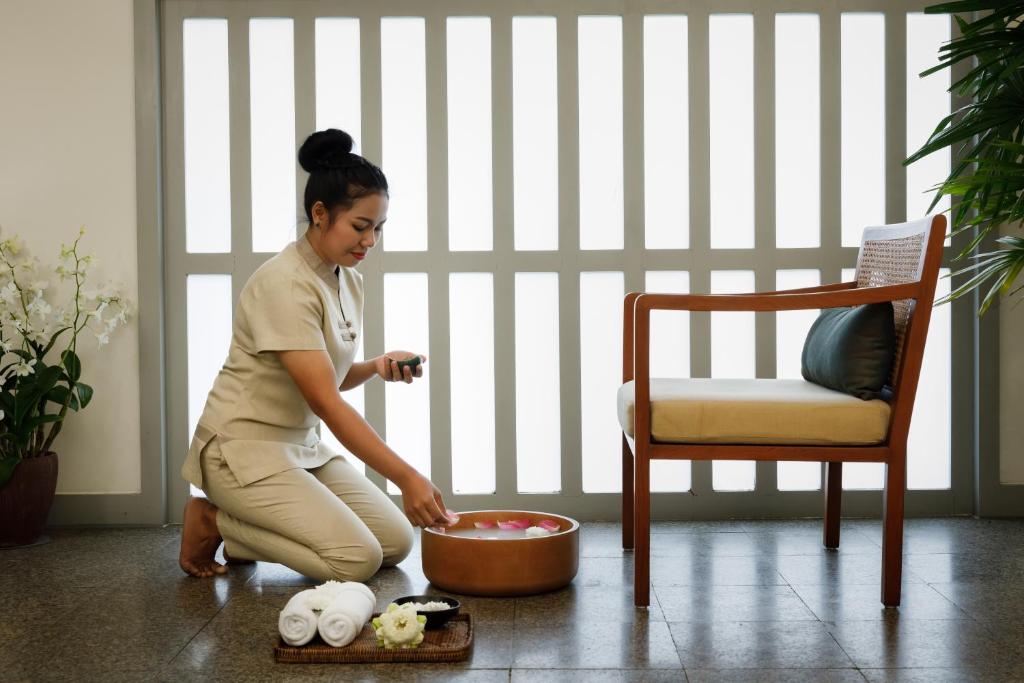 a woman sitting on the floor next to a bowl of food at The Surin Phuket in Surin Beach