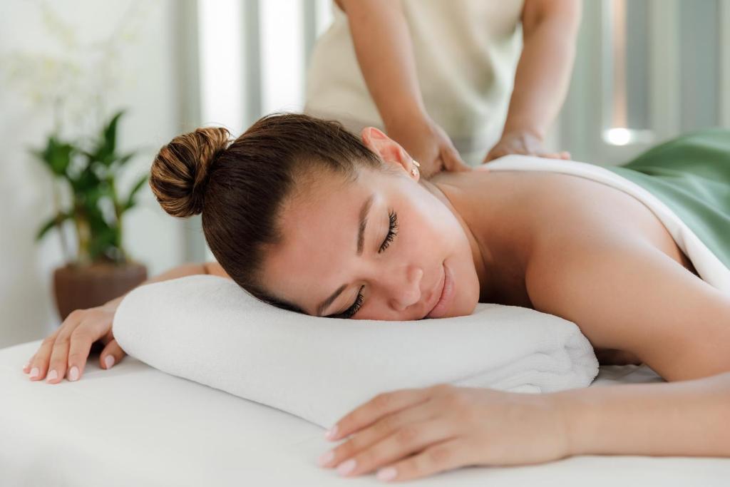 a woman laying on a pillow on a bed at The Surin Phuket in Surin Beach