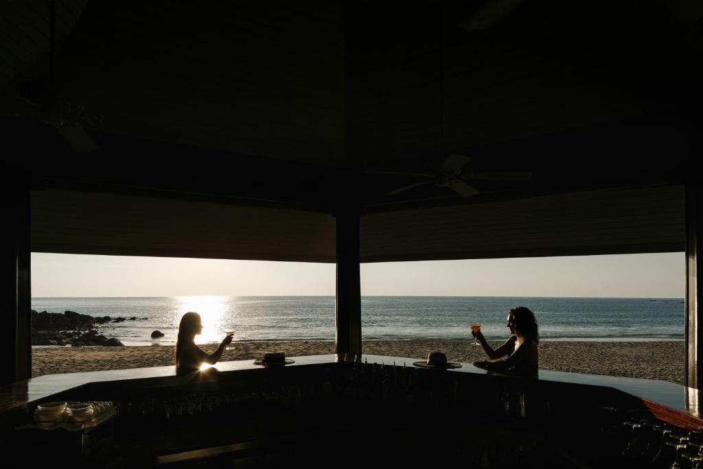 two women sitting at a table at the beach at The Surin Phuket in Surin Beach