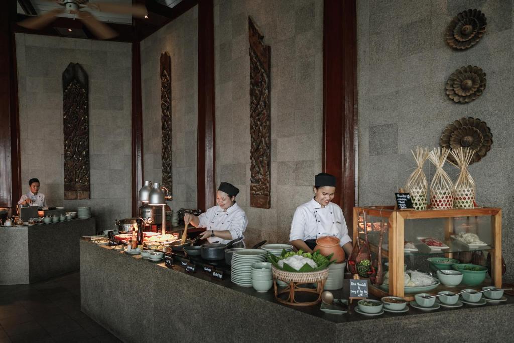 two chefs standing in a kitchen preparing food at The Surin Phuket in Surin Beach