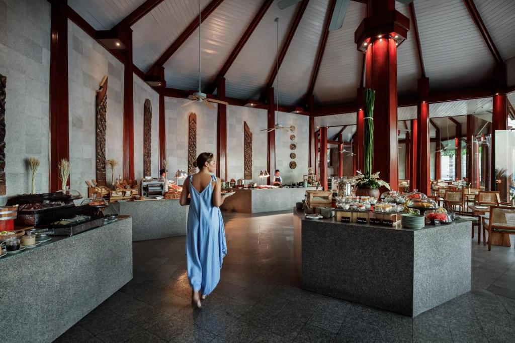 a woman in a blue dress walking through a restaurant at The Surin Phuket in Surin Beach
