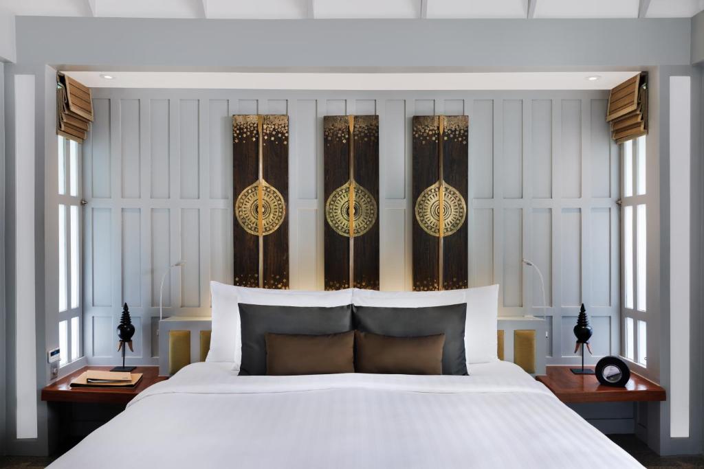 a bedroom with a large white bed and windows at The Surin Phuket in Surin Beach
