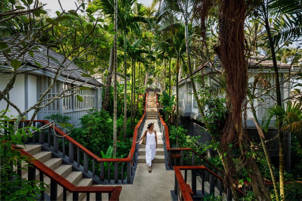 a woman walking down a bridge in a garden at The Surin Phuket in Surin Beach
