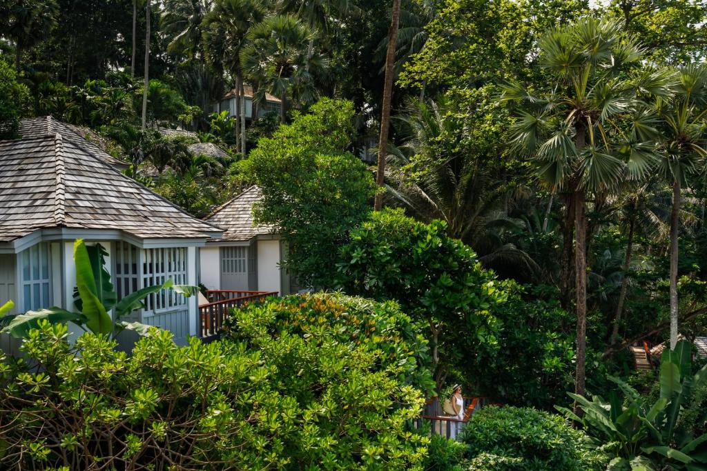 a woman standing in front of two houses in the trees at The Surin Phuket in Surin Beach