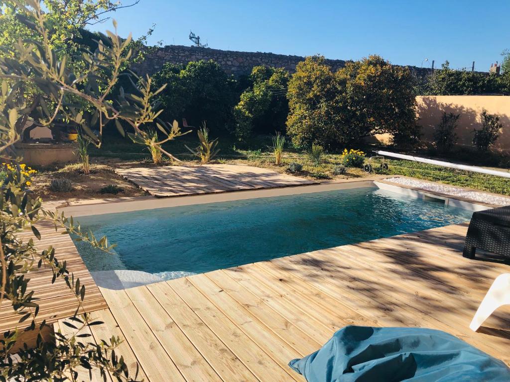una piscina en un patio con terraza de madera en Villa Les Oliviers en Salses-le-Chateau