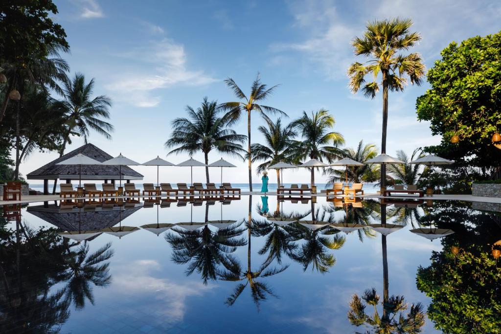 a pool at the resort with palm trees and chairs at The Surin Phuket - SHA Extra Plus in Surin Beach