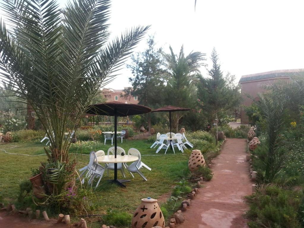 um jardim com uma mesa e cadeiras e um guarda-sol em d'hôte Jnane-Dar Diafa em Tamgrout