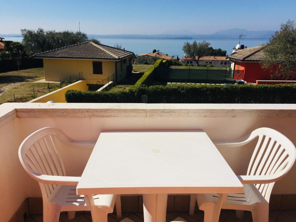 un tavolo bianco e 2 sedie sul balcone di Frida's Apartment a Bardolino