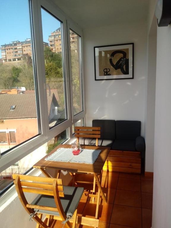 ein Wohnzimmer mit Tisch und Stühlen und Fenstern in der Unterkunft Apartamento Andoaga in San Sebastián