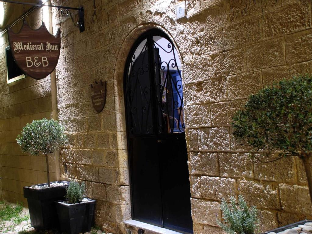 eine schwarze Tür an der Seite eines Steingebäudes in der Unterkunft Medieval Inn in Rhodos (Stadt)