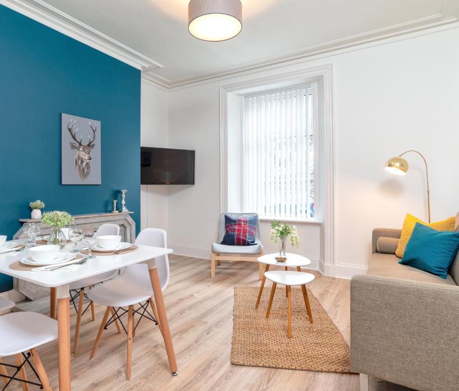 uma sala de estar com uma mesa e um sofá em West Mount Apartments em Aberdeen