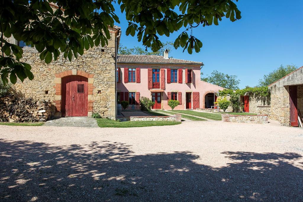 une grande maison avec une porte rouge et une allée. dans l'établissement Domaine Anguyales, à Montmaur