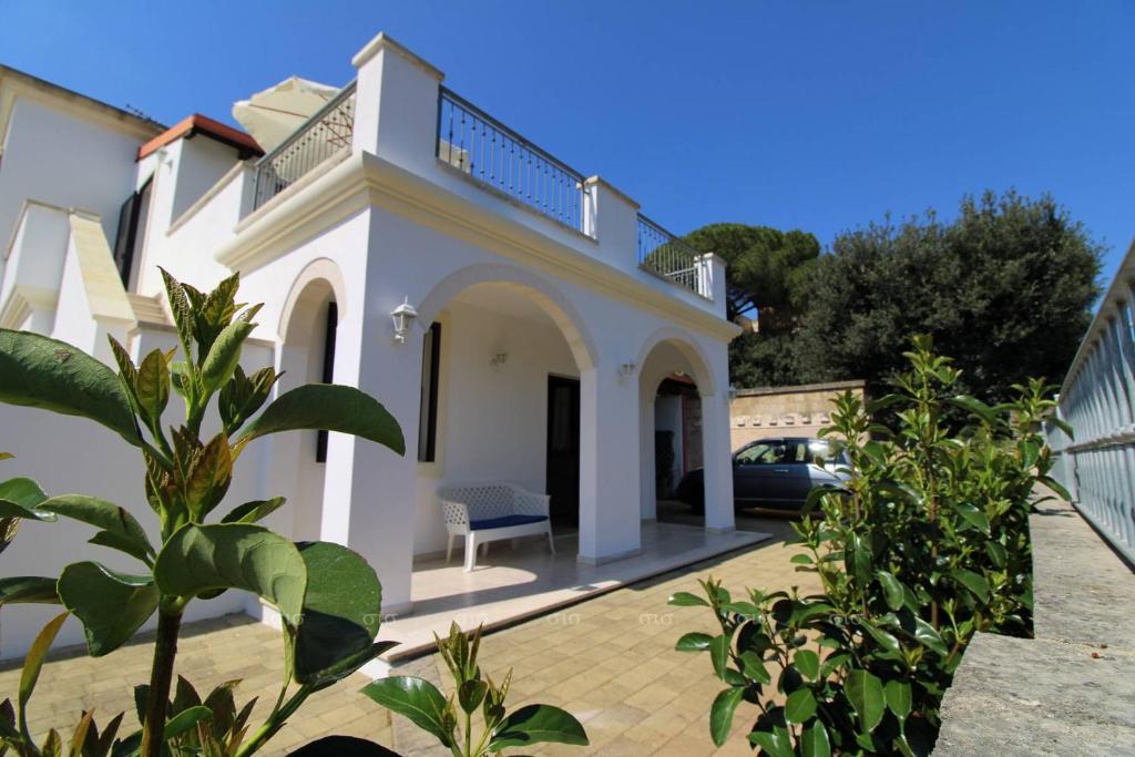 a white house with a car parked in the driveway at Borgo Cenate in Santa Caterina di Nardò