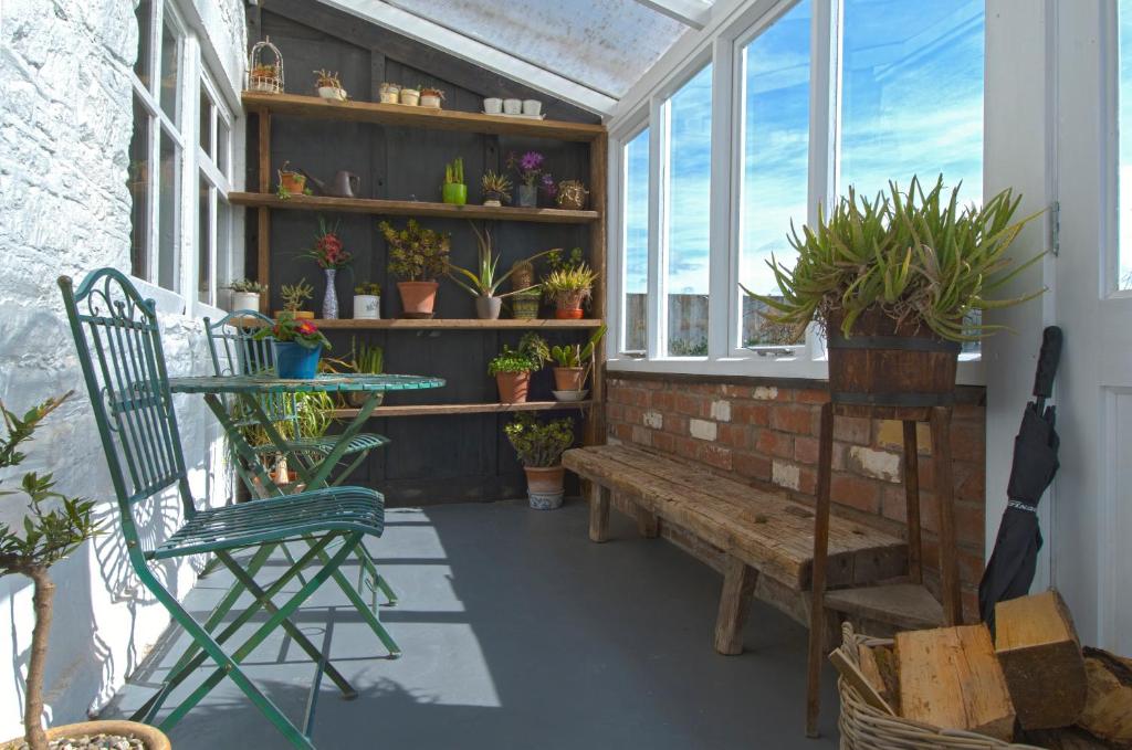 a porch with a bench and a window with potted plants at The Old Farm House in Hereford