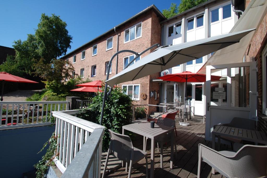 eine Terrasse mit Tischen und Stühlen und ein Gebäude in der Unterkunft Flensbed Hostel & Boardinghouse in Flensburg