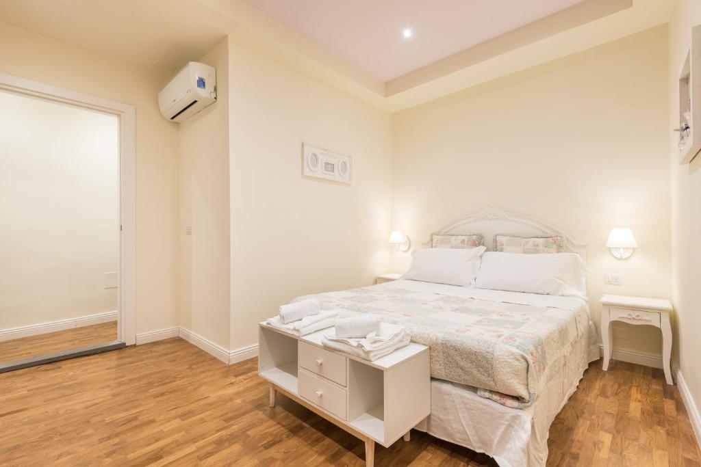 a white bedroom with a large bed and a table at Dimora Sant'Orsola in Florence