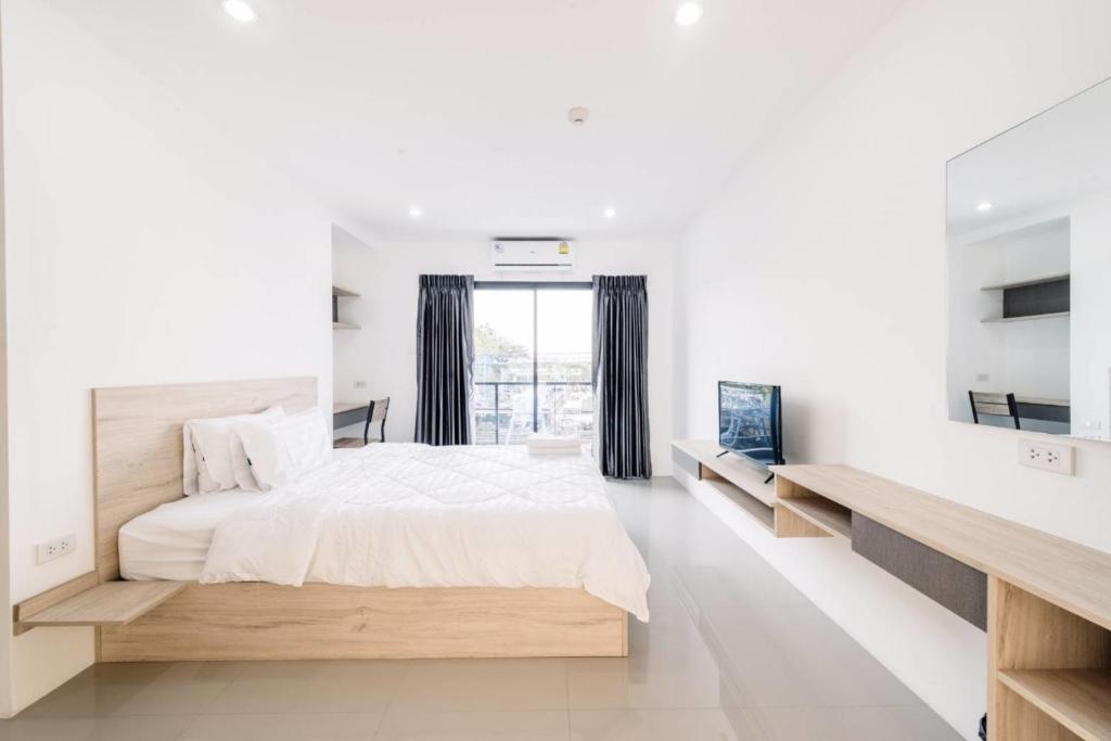 - une chambre blanche avec un grand lit et une fenêtre dans l'établissement Baan Mae Suvarnabhumi Airport, à Lat Krabang