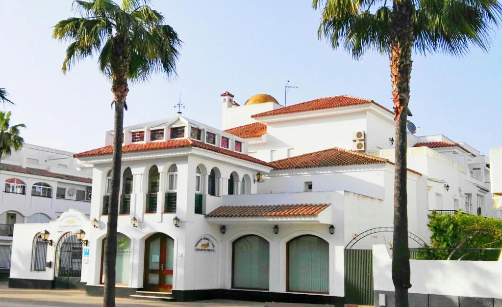 un edificio blanco con palmeras delante en Dunas y Luz, en Rota