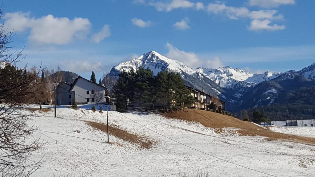 a house on a snowy hill with mountains in the background at Un "gioiello" di fronte alle Dolomiti in Carano