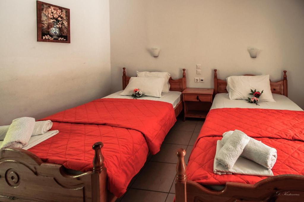 two beds in a room with red comforter at Musses in Kokkino Nero