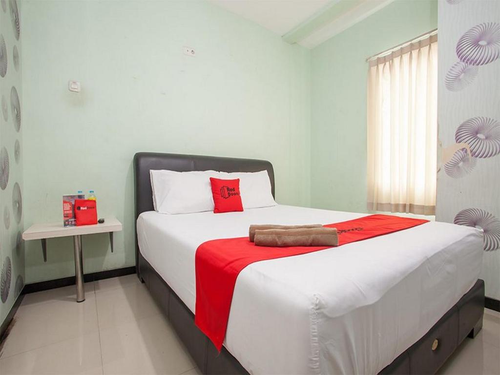 a bedroom with a large bed with a red blanket at RedDoorz @ Raya Tidar in Malang