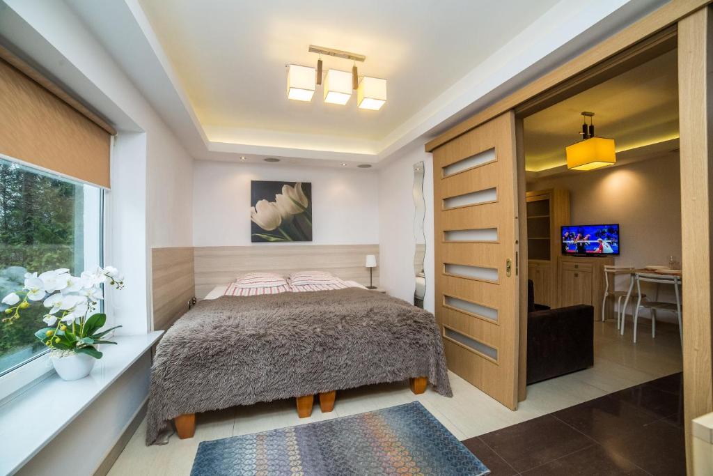 een slaapkamer met een bed, een raam en een tafel bij Apartamenty Barbara in Karwia